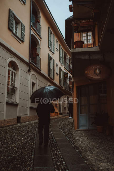 Man walking with umbrella on town street — Stock Photo