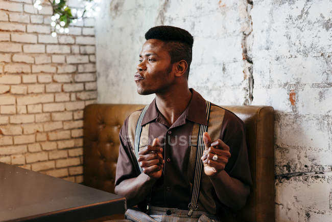 Человек в классической одежде сидит в кафе — стоковое фото