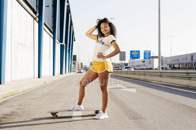 Teenage girl with skateboard standing on road — Stock Photo