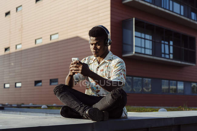 Homem em fones de ouvido usando smartphone — Fotografia de Stock