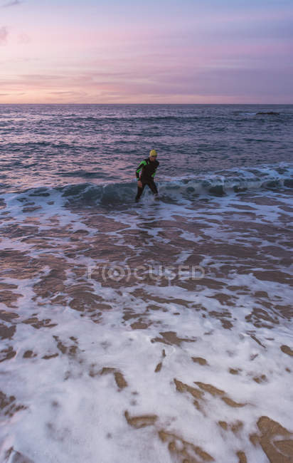 Triathlete standing in sea surf — Stock Photo