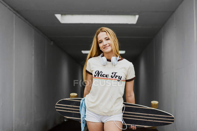 Blond girl with longboard under lamplight — Stock Photo