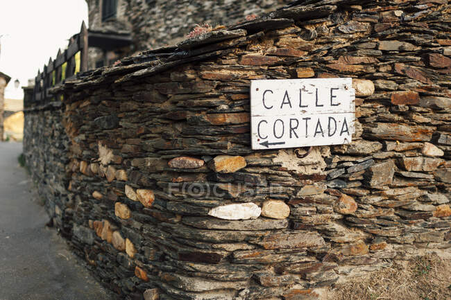 Stone decorated wall with Calle Cortada (street blocked) sign hanging in countryside. — Stock Photo