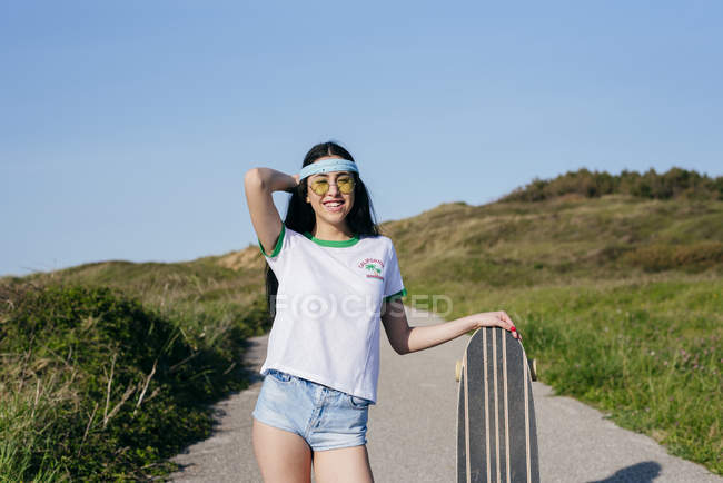 Mädchen mit Longboard steht auf Straße — Stockfoto