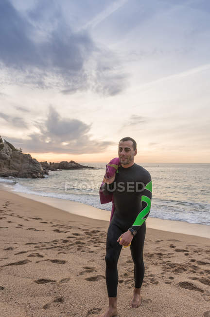 Триатлонист гуляющий по песчаному пляжу — стоковое фото
