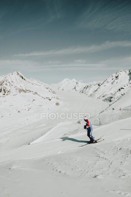 Vue latérale d'un sportif méconnaissable chevauchant du snowboard sur une montagne enneigée en hiver, Glaciar Aletsch desde el viewpoint de Eggishorn en Fiesch, Suisse — Photo de stock