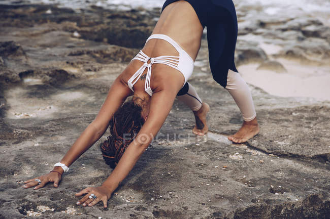 Женщина растягивается и позирует на берегу моря — стоковое фото