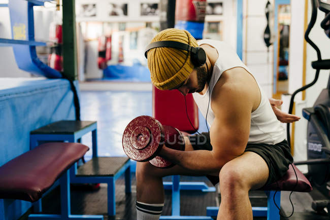 Чоловік займається з гантелі в спортзалі — стокове фото