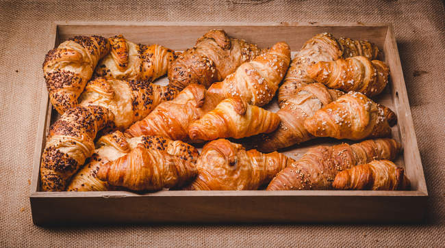 Mix of golden croissants in wooden tray — Stock Photo