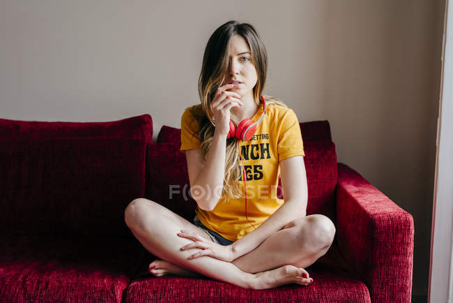Жінка з навушниками сидить на дивані — стокове фото