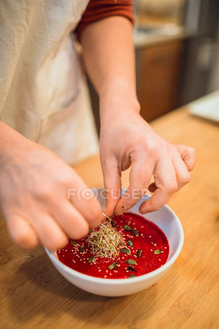 Mãos que põem temperos à sopa — Fotografia de Stock