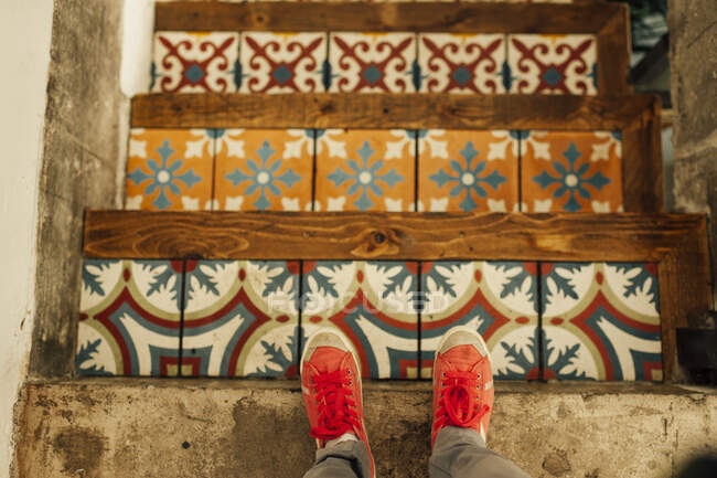 From above legs in sneakers standing at colorful tiled steps. — Foto stock