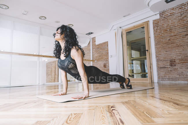 Frau praktiziert Yoga auf Matte im Unterricht — Stockfoto