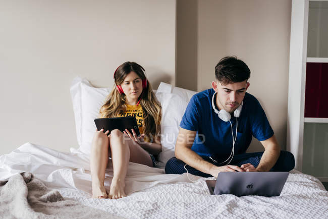Couple utilisant des gadgets au lit — Photo de stock