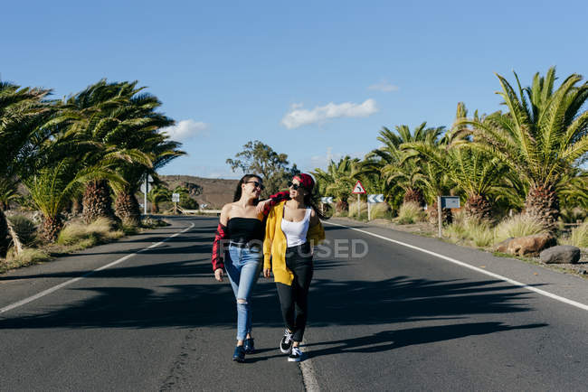 Mulheres andando na estrada ensolarada — Fotografia de Stock