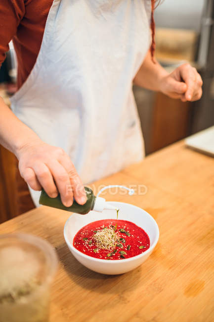 Hand putting green oil to soup — Stock Photo