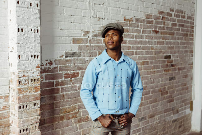Homme noir debout contre un mur de briques — Photo de stock