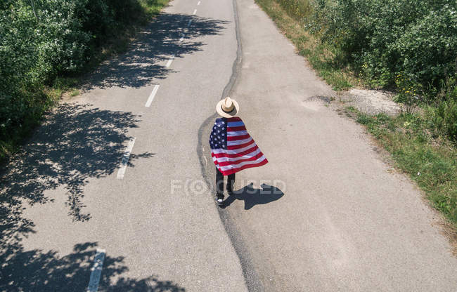 Человек в шляпе ходит с американским флагом — стоковое фото