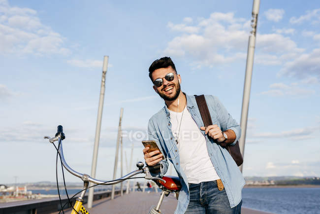 Парень с велосипедом и смартфоном — стоковое фото