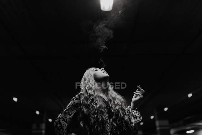 Гарненька руда жінка курить на розмитій парковці . — стокове фото
