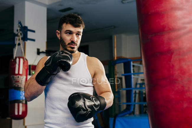 Hombre saco de boxeo en gimnasio - foto de stock