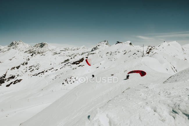 Touristen mit Fallschirmen stehen am verschneiten Hang — Stockfoto