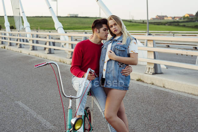 Пара, стоящая на мосту с винтажным велосипедом — стоковое фото