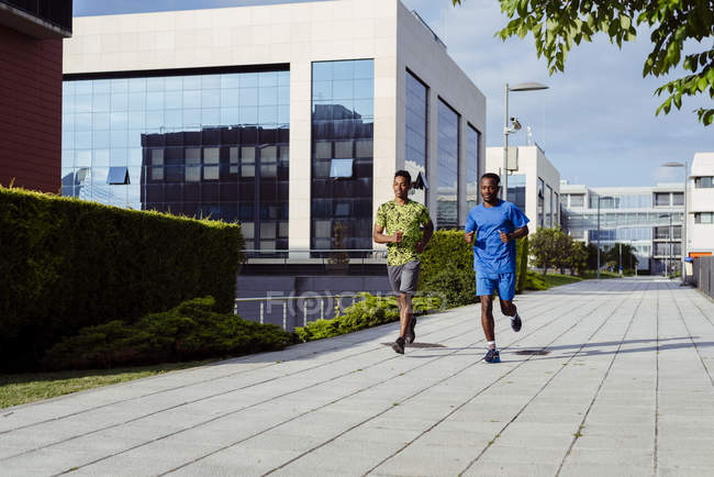 Uomini etnici che fanno jogging insieme sulla strada moderna — Foto stock
