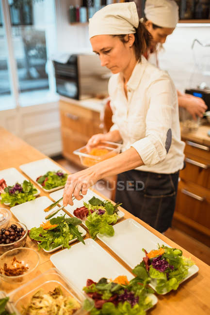 Woman serving plates with vegan snacks — Stock Photo