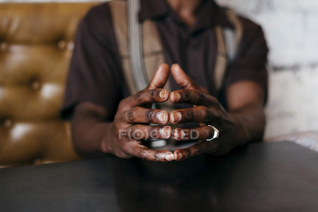 Folding hands of sitting black man — Stock Photo