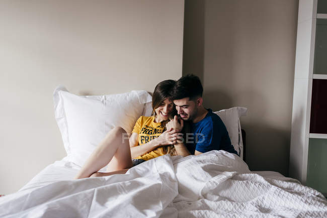 Sorrindo casal deitado na cama — Fotografia de Stock