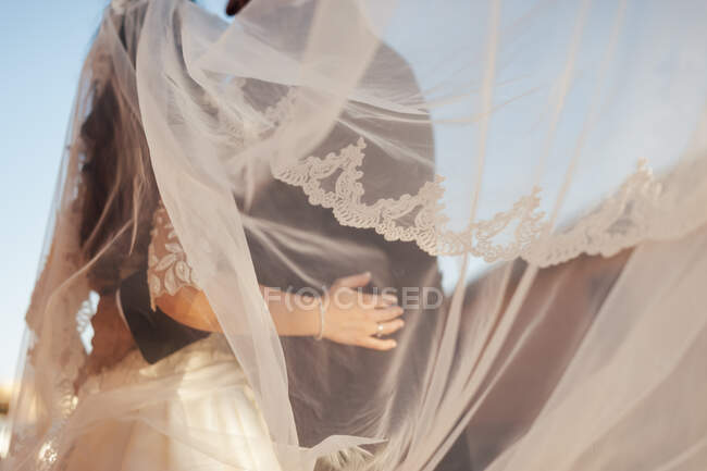 Mão de noivo irreconhecível abraçando noiva em vestido branco. — Fotografia de Stock