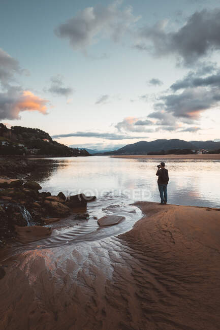 Людина на спокійному пляжі на заході сонця — стокове фото