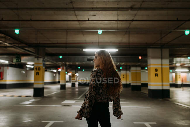 Atractiva joven mujer de pie en el estacionamiento con un bengala. - foto de stock