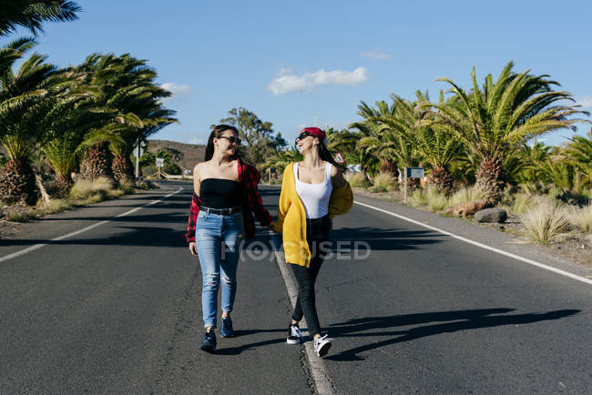 Mulheres andando na estrada ensolarada — Fotografia de Stock
