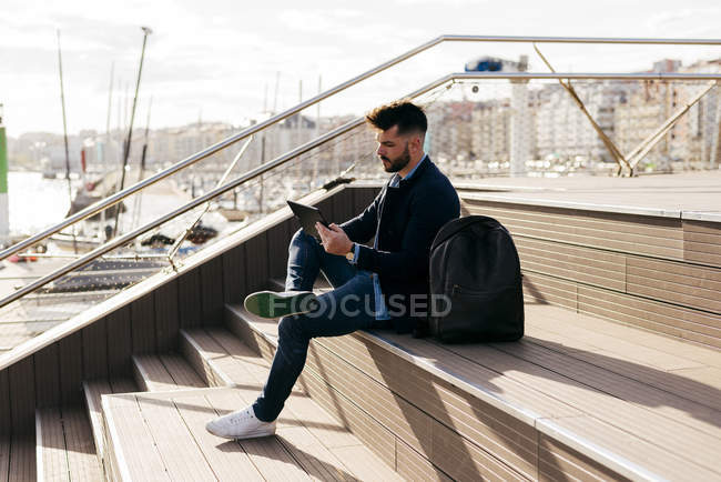 Hombre con estilo utilizando la tableta en el puerto - foto de stock