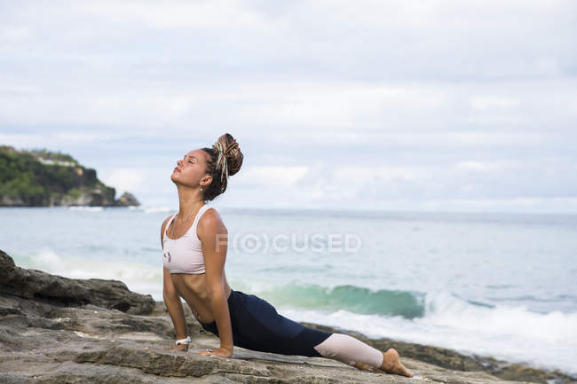 Жінка розігрівається на пляжі в океані — стокове фото