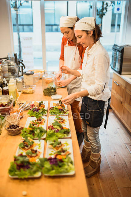 Mulheres de pé e servindo pratos — Fotografia de Stock