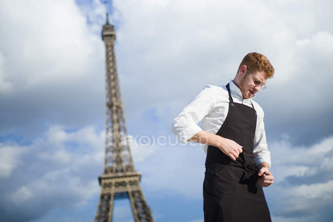 Cocinero pelirrojo vistiendo uniforme frente a la Torre Eiffel en París - foto de stock