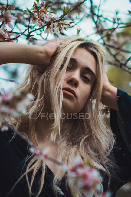 Portrait de femme blonde en fleurs touchant la tête — Photo de stock