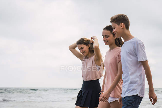 Улыбающиеся подростки, идущие вместе по пляжу — стоковое фото