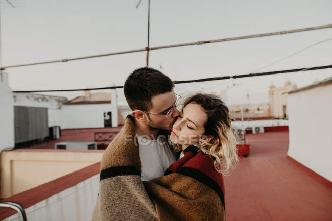 Пара обнимается с одеялом на террасе — стоковое фото
