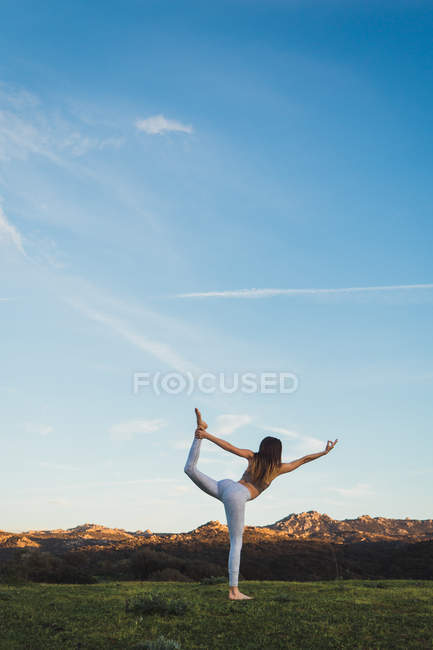 Mujer estiramiento en una pierna en el césped en la naturaleza - foto de stock