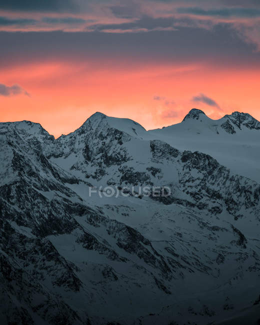 Montanhas cobertas de neve sob o céu dramático ao pôr do sol — Fotografia de Stock