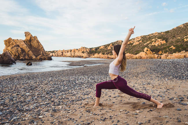 In forma giovane donna che esercita sulla spiaggia — Foto stock