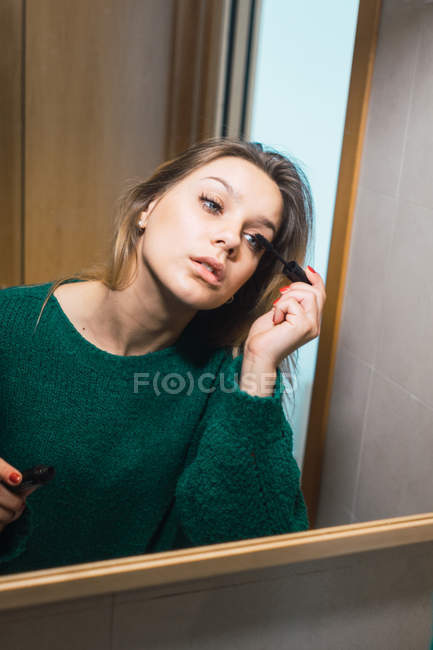 Случайная женщина наносит тушь в ванной комнате — стоковое фото