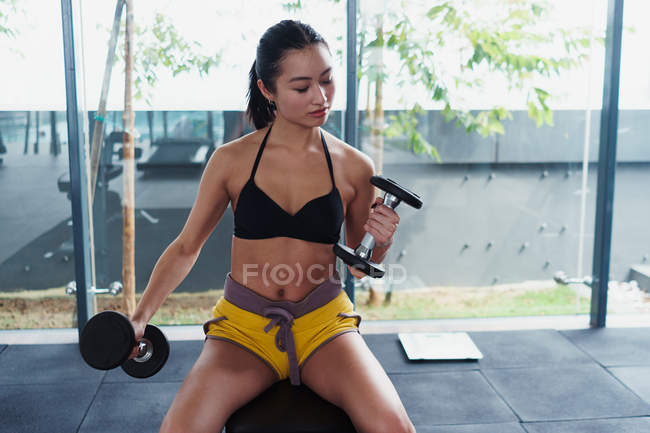 Mulher asiática bonita e exercitando-se com halteres no ginásio — Fotografia de Stock