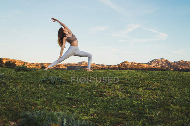 Fit woman stretching on lawn in nature — Stock Photo