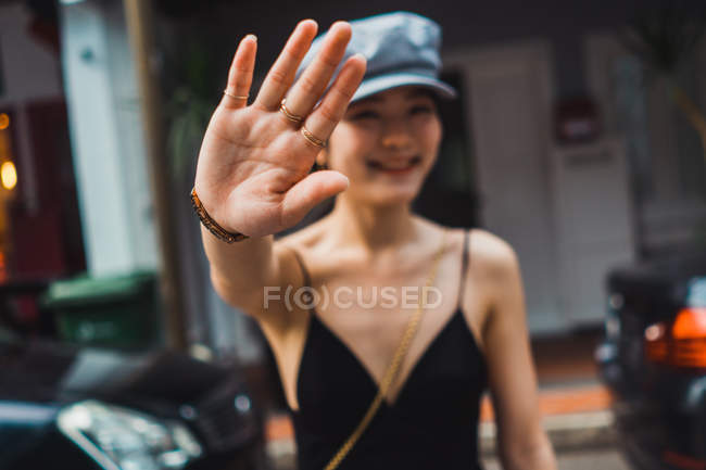 Atractiva joven asiática caminando por la calle con el brazo extendido - foto de stock
