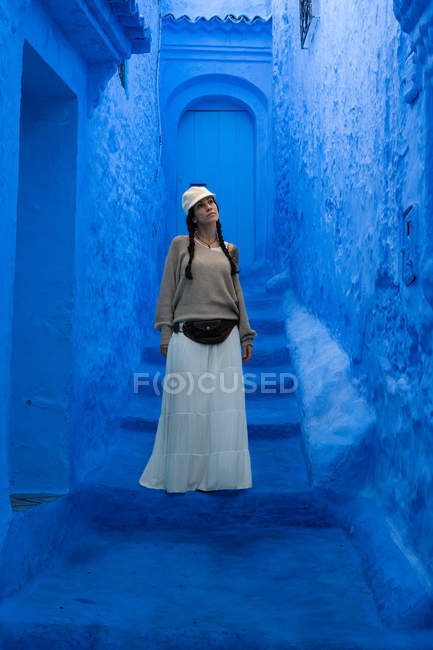 Woman wearing cap and long skirt walking on Moroccan city dyed blue — Stock Photo